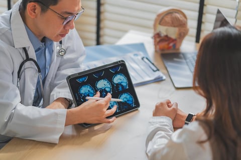 Doctor explaining brain MRI scan on tablet to patient during consultation