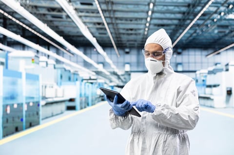 Indian technician in microchip factory testing silicon wafer batches with tablet control app