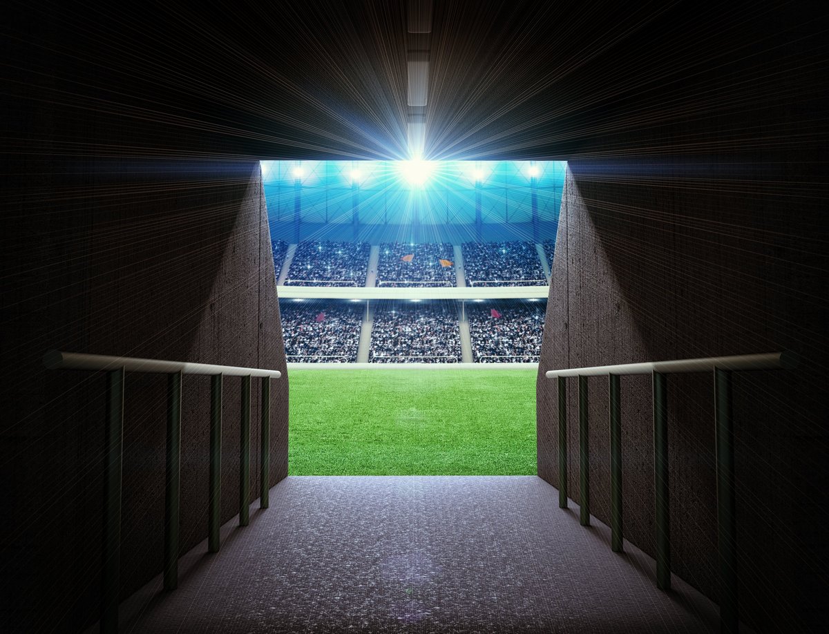 Empty stadium tunnel with atmospheric lighting leading toward the field