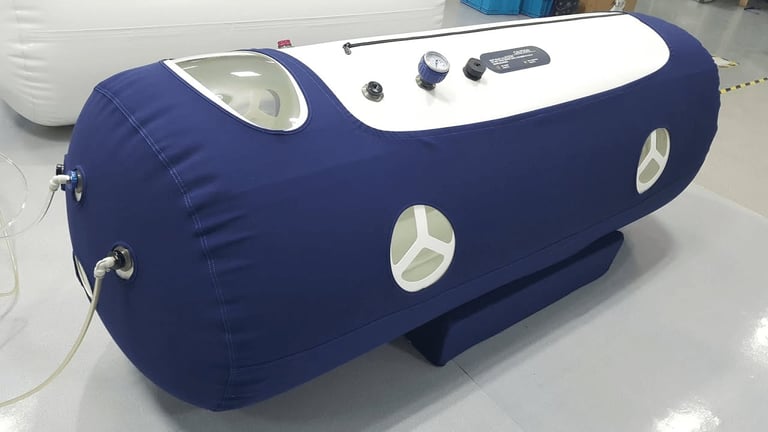 Navy blue cylindrical hyperbaric oxygen chamber with control panel and circular porthole windows